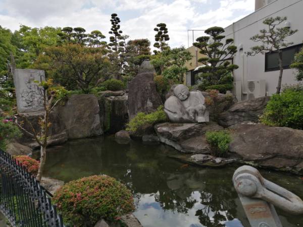 松の木や立派な庭石や石像に囲まれた池