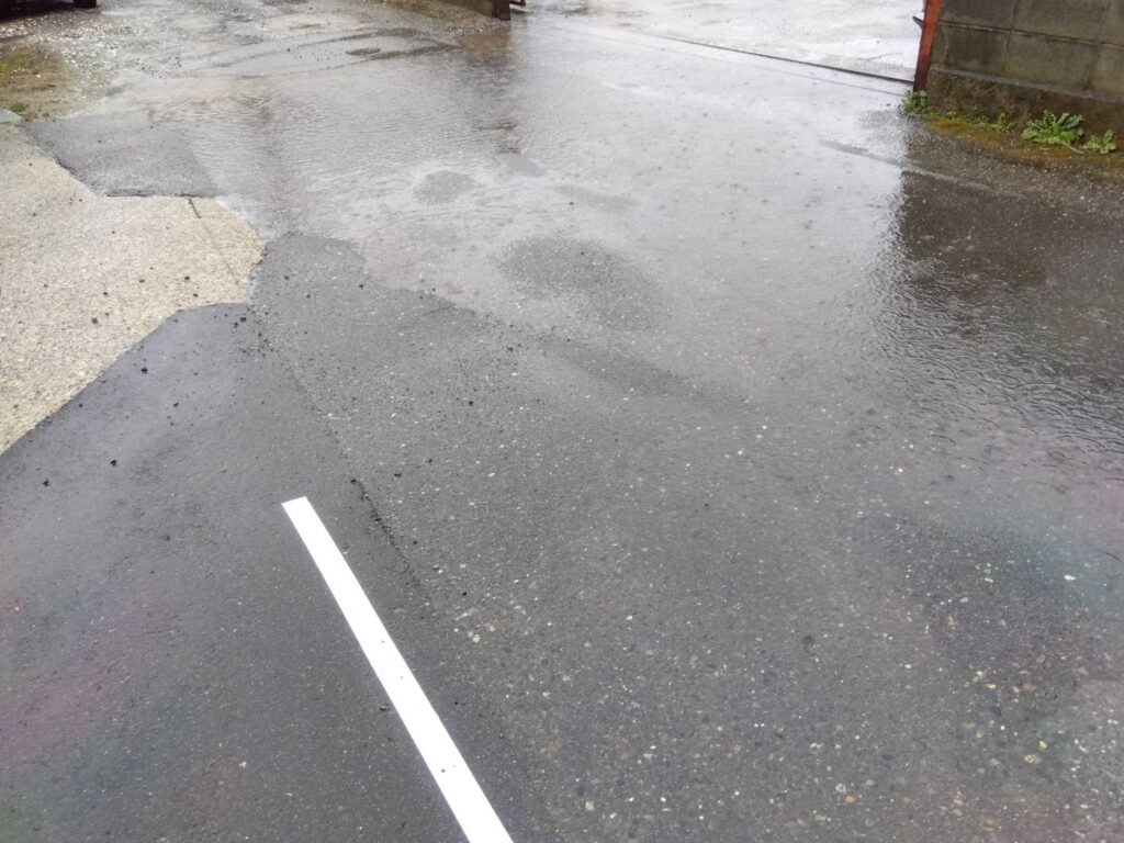 雨の日の道路と水たまりの写真